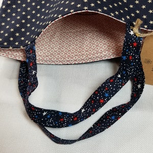 May include: A blue and white tote bag with a red, white and blue star pattern on the straps. The bag is lined with a red and white diamond pattern.