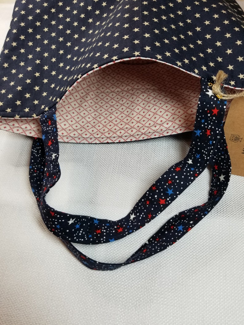 May include: A blue and white tote bag with a red, white and blue star pattern on the straps. The bag is lined with a red and white diamond pattern.