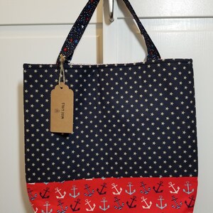 May include: A blue and red tote bag with white stars and anchors. The bag has a brown tag that says "Wise Girl Gifts".