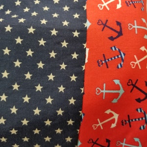 May include: A red fabric with a white and blue anchor pattern. The fabric is sewn to a navy blue fabric with a white star pattern.