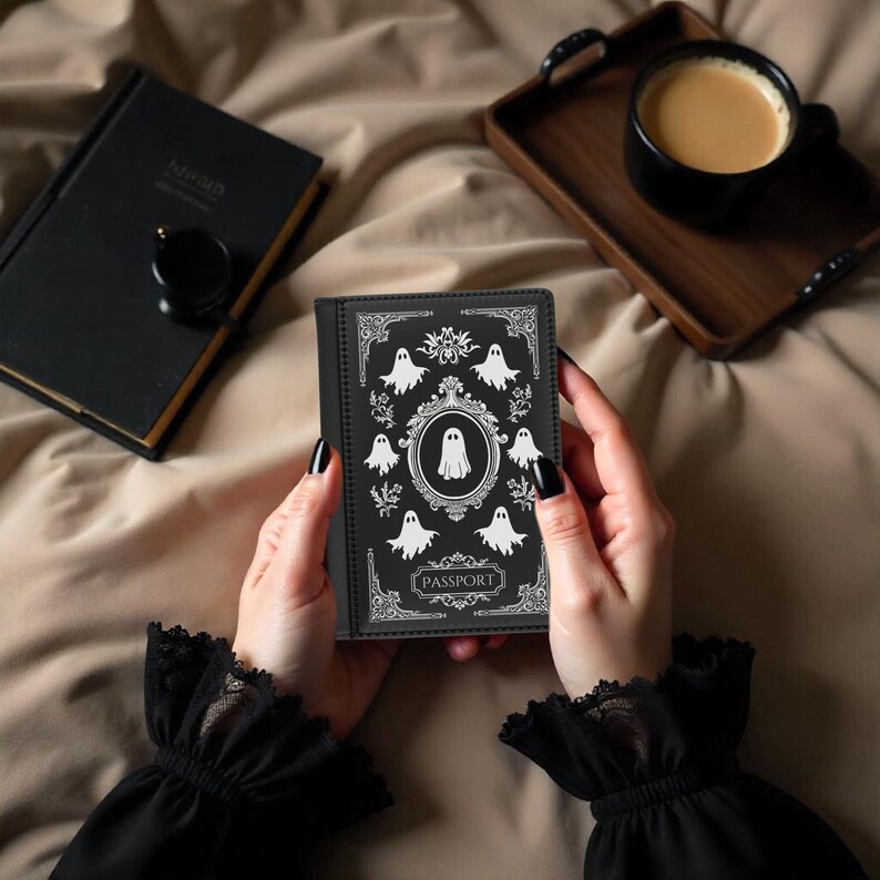 May include: Black passport holder with a white design of ghosts and the word "PASSPORT" on the front.
