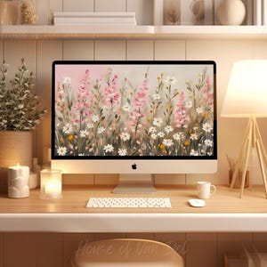 May include: A desktop computer with a white background and a screen displaying a painting of pink and white flowers. The computer is on a wooden desk with a white keyboard, a white mouse, and a white cup.