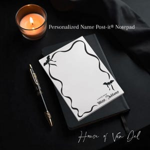 May include: A white Post-it® notepad with a black wavy border and bat illustrations, labeled "A NOTE FROM Miss. Addams." The notepad rests on a black notebook, with a pen and candle nearby. Text reads "Personalized Name Post-it® Notepad."