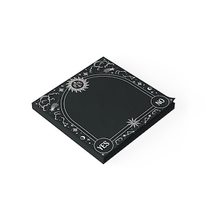 May include: A square black notepad featuring a white celestial border design with a sun, stars, clouds, and constellations. The bottom corners contain circular icons with the text YES and NO printed in white, set against a dark background.