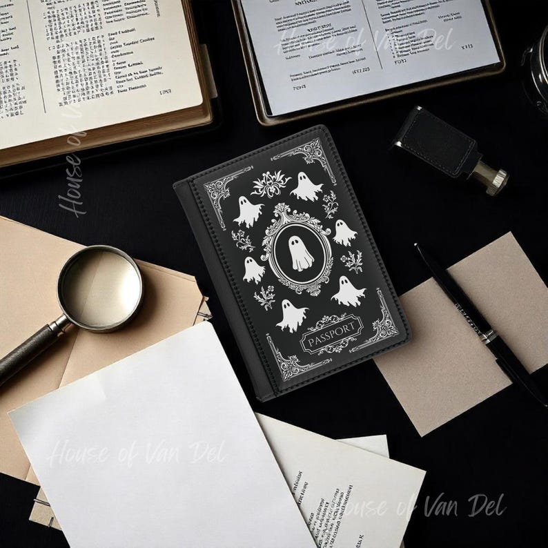 May include: Black passport holder with a white ghost design and the word "PASSPORT" printed on the front.