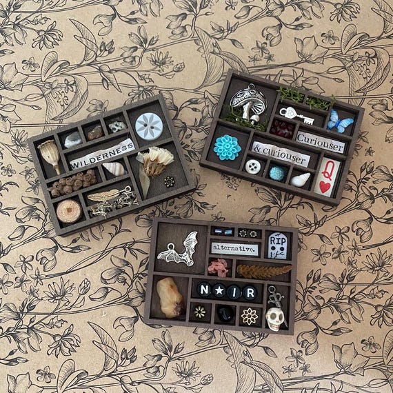 A tiny vintage-style printer's tray turned into a curated micro-shelf of crystals and natural treasures — a dollhouse-scale cabinet of curiosities.