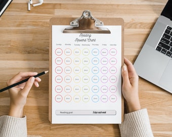 May include: A reading reward chart with a clipboard, a pencil, and a laptop. The chart has a grid of circles with the days of the week and the number 20 written in each circle. The text "Reading Reward Chart" is at the top of the chart. The text "Reading goal: 5 days each week" is at the bottom of the chart.
