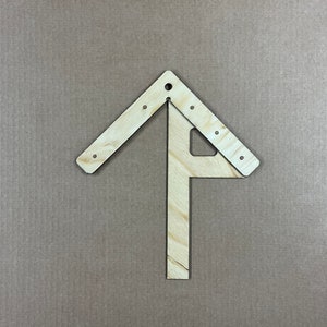 May include: A wooden tool with a triangular shape and a straight piece extending from the bottom. The tool is made of light wood and has several small holes along the edges.