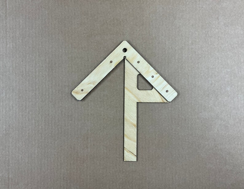 May include: A wooden tool with a triangular shape and a straight piece extending from the bottom. The tool is made of light wood and has several small holes along the edges.