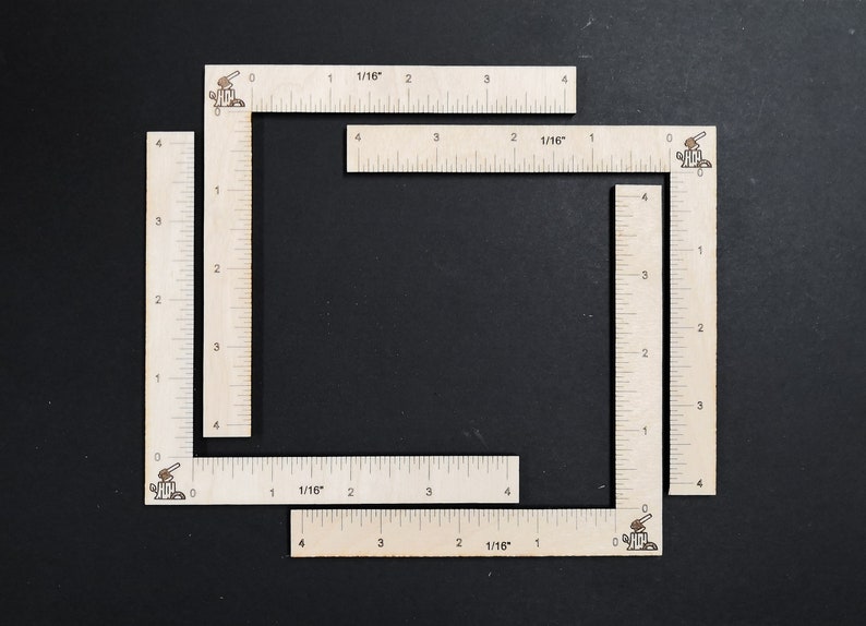 May include: Four wooden rulers with markings in inches and 1/16ths of an inch. The rulers are arranged in a square shape.