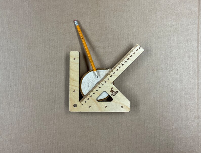 May include: A wooden protractor with a pencil and a wooden circle with concentric rings. The protractor has markings in inches and the circle has a diameter of approximately 10 cm.