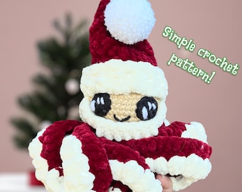 Könnte beinhalten: Ein gehäkelter Oktopus, der einen Weihnachtsmann-Hut trägt. Der Oktopus ist rot und weiß mit einem weißen Bommel auf dem Hut. Der Text "Einfaches Häkelmuster!" ist in Grün auf weißem Hintergrund geschrieben.