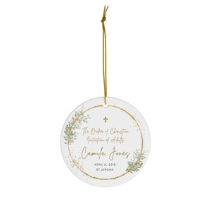 May include: White ceramic ornament with a gold circle and green leaves around the edge. The text reads "The Order of Christian Initiation of Adults Camila Jones April 8, 2018 St. Jerome".