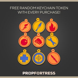 May include: Nine colorful keychain tokens with various designs, including a flame, wrench, and cross, are displayed on a dark background. The text "FREE RANDOM KEYCHAIN TOKEN WITH EVERY PURCHASE!" is at the top, and the Prop Fortress logo is at the bottom.