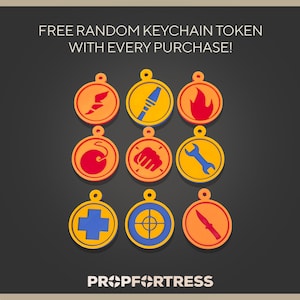 May include: Nine colorful keychain tokens with various designs, including a flame, wrench, and cross, are displayed on a dark background. The text "FREE RANDOM KEYCHAIN TOKEN WITH EVERY PURCHASE!" is at the top, and the Prop Fortress logo is at the bottom.