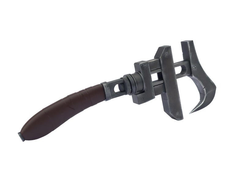 May include: A dark gray adjustable wrench with a brown handle. The wrench has a curved, pointed end and a mechanism to adjust the jaw size. The handle is wrapped in a textured brown material.