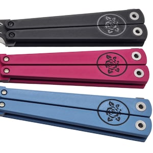 Op de afbeelding: Drie vlindermessen in zwart, roze en blauw. Elk mes heeft een rozenembleem op het handvat en een bloemmotief op het lemmet. De handvatten zijn rechthoekig met afgeronde randen en hebben twee gaten voor de schroeven.