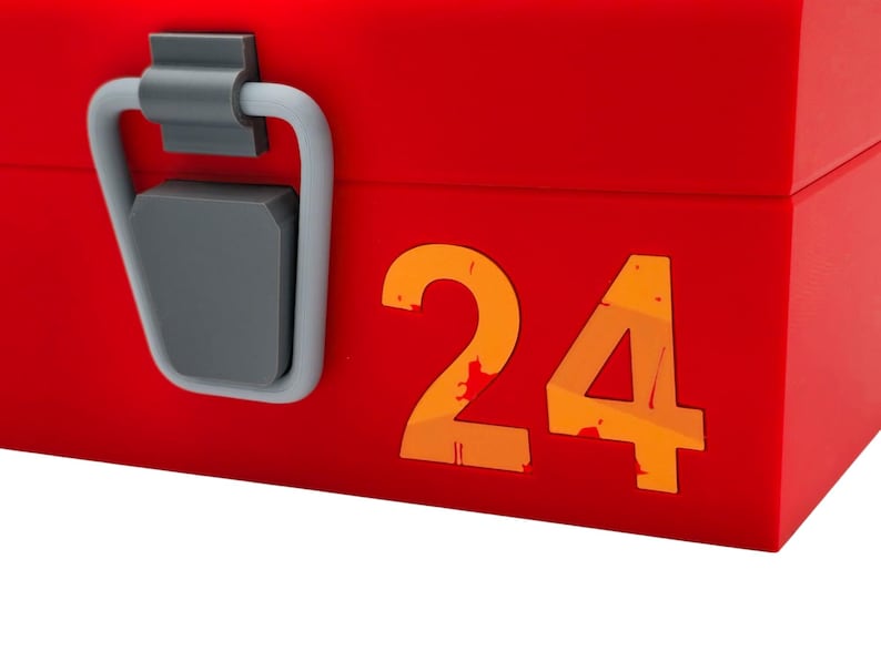 May include: A red box with a gray handle and latch. The number "24" is printed in orange on the side of the box. The box is likely used for storage or display.