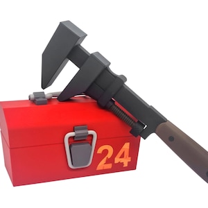 May include: A red toolbox with a gray handle and the number "24" in orange. A black adjustable wrench with a brown handle rests on top of the toolbox. The wrench is angled across the toolbox.