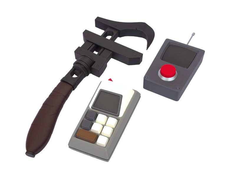 May include: A black adjustable wrench with a brown handle, a gray remote control with a red button, and a gray calculator with white and brown buttons. The objects are set against a white background.