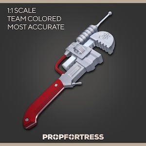 May include: A silver and red prop wrench with a unique design. The wrench features a red handle, silver body, and a distinctive top with a small antenna-like element. The text "1:1 SCALE TEAM COLORED MOST ACCURATE" is visible.