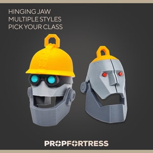 May include: Two robot head props with hinged jaws. One has a yellow hard hat and blue glowing eyes, the other has red eyes. Text reads "HINGING JAW MULTIPLE STYLES PICK YOUR CLASS" and "PROP FORTRESS".