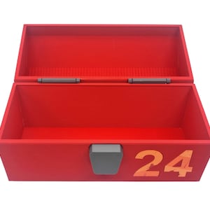 May include: A red wooden toolbox with an open lid. The box has a gray latch and the number "24" in orange on the front. The interior of the box is also red.