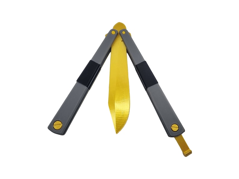 May include: A butterfly knife with a gold blade and gray handles. The handles have black accents and gold-colored screws. The blade is in the open position, showcasing its full length.