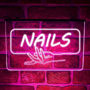 Może przedstawiać: Różowy neonowy znak z napisem "NAILS" w białych neonowych literach. Pod napisem znajduje się stylizowana dłoń z zadbanymi paznokciami.