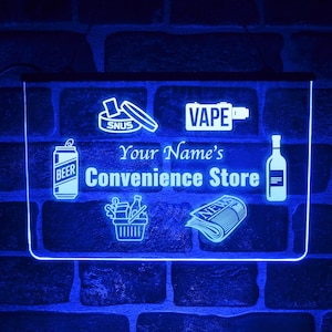 Könnte beinhalten: Blaues Neon-Schild für einen Kiosk mit beleuchteten Symbolen für Bier, Vape, Snus, eine Flasche, einen Einkaufskorb und eine Zeitung. Der Text "Your Name's Convenience Store" ist zentriert.