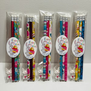 May include: Five sets of three pencils wrapped in cellophane bags. Each set includes a blue and white patterned pencil, a pink and white patterned pencil, and a purple and white patterned pencil. Each set also includes a small white bunny eraser. Each bag has a round sticker with a cartoon bunny holding an Easter egg and the text "Happy Easter" and "From: Brian".