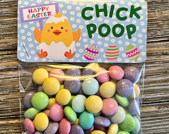 Puede incluir: Una pequeña bolsa de plástico transparente llena de caramelos de colores pastel. La bolsa tiene una tarjeta azul y blanca adjunta con un pollito de dibujos animados y el texto "Feliz Pascua" y "Caca de Pollo".