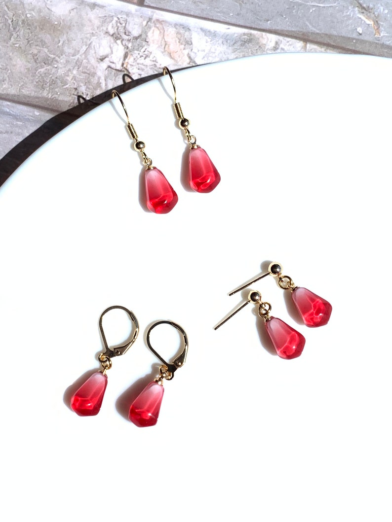 Pode incluir: Quatro pares de brincos com um design de semente de rom&atilde;. Os brincos t&ecirc;m metal dourado e uma conta vermelha transl&uacute;cida em forma de gota. Dois pares t&ecirc;m fecho de gancho e dois pares t&ecirc;m fecho de pino.