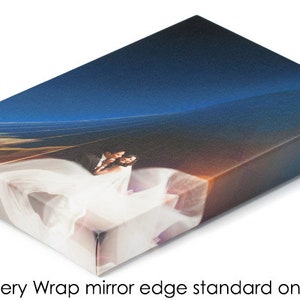 May include: A 1.5 inch gallery wrap canvas print with a mirror edge. The print features a couple in a white dress and a blue suit, standing in front of a blue and orange sky.