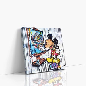 May include: A colorful painting of Mickey Mouse painting a self-portrait on a canvas. The background is white with black splatters of paint. Mickey Mouse is wearing his signature red shorts and yellow shoes.