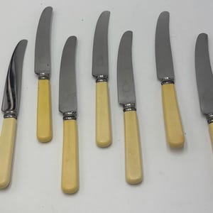 Seven Vintage Butter Knives with Ivory Colored Celluloid/Bakelite Handles and Stainless Steel Blades.