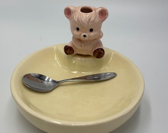 Najsłodsze, zabytkowe naczynie dla dziecka z łyżeczką i uroczym misiem z korkiem, który służy również jako podstawka pod łyżeczkę. Wlej do środka ciepłą wodę, aby jedzenie było ciepłe.