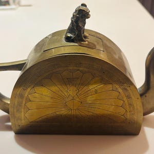 May include: A white ceramic mug with a black handle and the text "But First, Coffee" in a bold, black font. The mug is sitting on a wooden surface. The mug is approximately 4 inches tall.