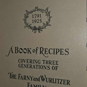May include: Close-up of a book cover with the title "A Book of Recipes." The cover features the text "Covering Three Generations of The Farny and Wurlitzer Family." A decorative emblem with the dates 1791 and 1925 is also visible.