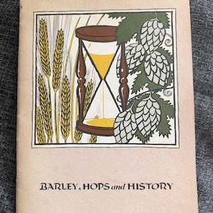 May include: A booklet cover with a light beige background featuring a central illustration of a brown hourglass, yellow wheat stalks on the left, and green hop cones on the right. The text at the bottom reads, BARLEY, HOPS and HISTORY.