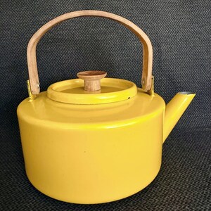 May include: A bright yellow kettle with a smooth, glossy finish, featuring a light-colored wooden arched handle and a matching wooden knob on the circular lid. The kettle has a short, angled spout and a cylindrical body with a flat base.