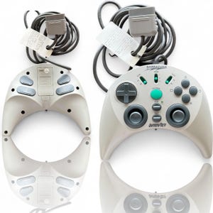 May include: Two off-white Interact Barracuda game controllers with gray cables and connectors. One controller is face up, displaying buttons and the text "Interact". The other is face down, showing the back.