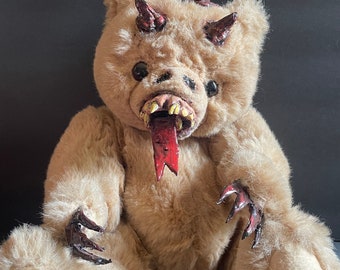 May include: A brown teddy bear with red antlers, horns, and a red tongue sticking out. The bear has claws and a menacing expression.