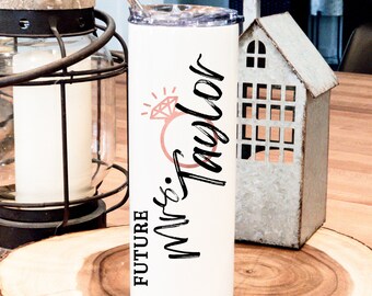 May include: White stainless steel tumbler with a black and pink design. The tumbler has the text "FUTURE Mrs. Taylor" and a pink diamond ring graphic.