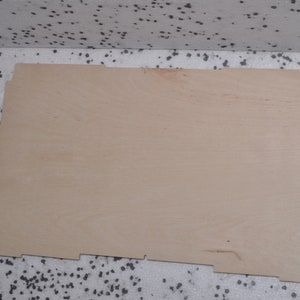 May include: A plain, light brown wooden board with a slightly rough texture. The board has a rectangular shape with slightly uneven edges.