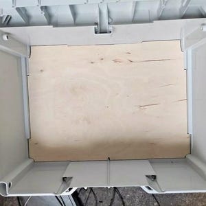 May include: A white plastic storage container with a wooden insert. The container has a hinged lid and a handle on the front.