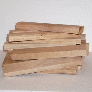 May include: A stack of unfinished, light brown wooden planks. The planks are approximately 1 inch thick and 12 inches long.