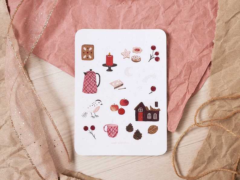 Puede incluir: Una tarjeta blanca con una variedad de ilustraciones pintadas a mano en rojo, marr&oacute;n y blanco. Las ilustraciones incluyen una tetera, un p&aacute;jaro, una casa, una vela, una estrella, una pi&ntilde;a, una taza y algunos otros objetos. La tarjeta tiene el texto "Liebe Weihnachten" en la parte inferior.
