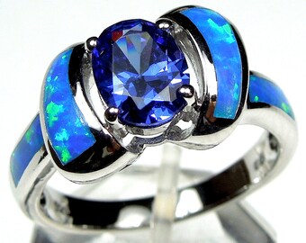Può includere: Un anello d'argento con una pietra ovale blu circondata da due bande di opale blu e verde.
