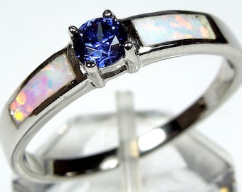 Può includere: Un anello d'argento con una pietra preziosa blu e due accenti di opale bianco.